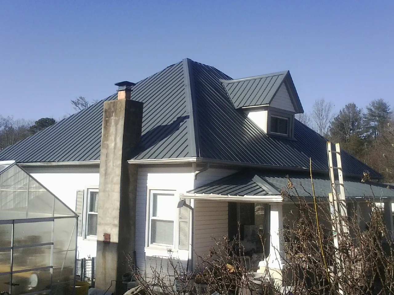 Dark blue standing seam metal roof on a white farmhouse with dormer — Slate & Tile Roof Repair by Roofing Brothers in Yerington