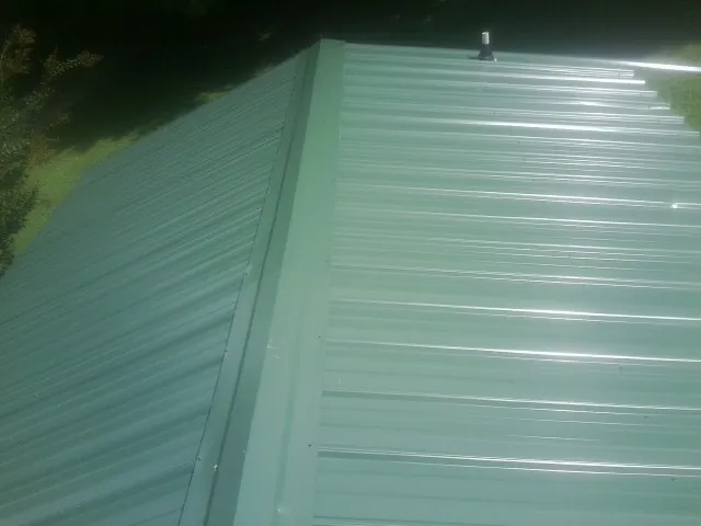 New green metal panels meeting at the ridge of a roof — Flat Roof Repair work by our crew in Yerington