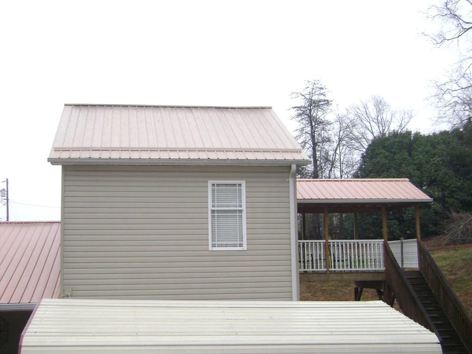 Tan metal roofs on a two story addition and attached porch, from a Roof Replacement job in Yerington