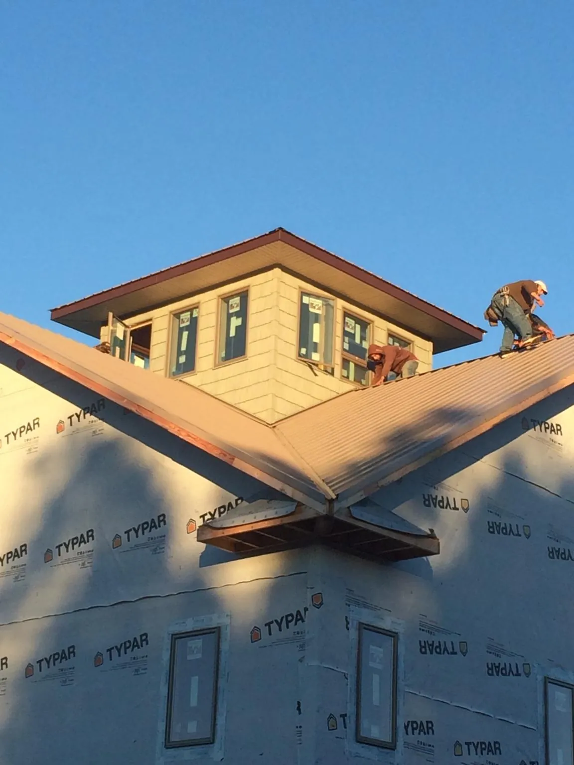 Roofers working around a rooftop cupola on a new metal roof at sunset — Roof Waterproofing in Yerington by Roofing Brothers